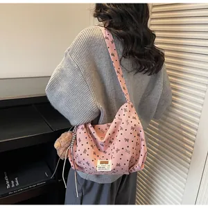 Rosa Cord-Umhängetasche mit Herz-Schleifen-Muster und Plüschbär-Anhänger an einem Model
