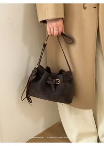 Détail d'un sac seau rétro en daim marron foncé avec boucle et glands en cuir élégants