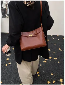 Détail d'un sac d'épaule en cuir marron foncé avec un fermoir tournant en métal doré
