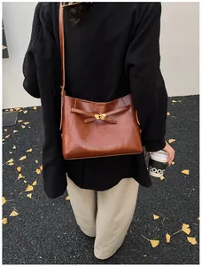 Sac à bandoulière en cuir marron avec boucle dorée dans une scène d'automne