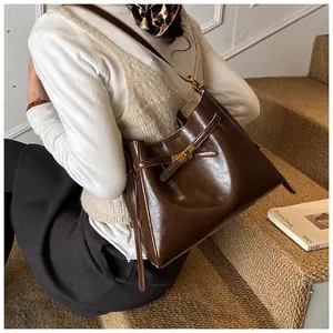 Sac fourre-tout en cuir brillant marron foncé avec fermoir rotatif doré porté