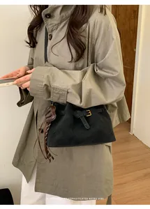 Détail d'un sac seau en daim noir avec pampille en cuir tressé et boucle de style rétro