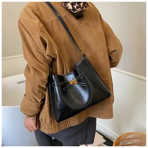 Détail du sac bandoulière en cuir PU noir brillant avec fermoir doré sur le mannequin