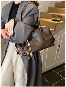 Detail of dark brown oil wax leather tote bag with dachshund charm and tassel accessory