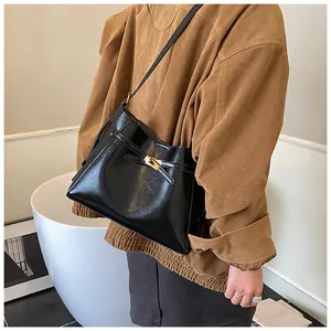 Détail d'un sac sous le bras noir brillant chic avec un fermoir rotatif doré