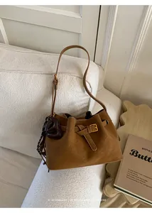 Détail du sac seau en daim marron avec boucle dorée et gland en cuir en forme de cœur