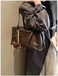Detailed view of dark brown faux leather tote with dachshund charm on grey blazer