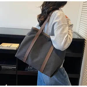 Modern canvas tote bag with brown leather straps shown on shoulder in stylish interior