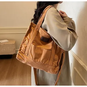 Close-up of caramel canvas tote bag detail featuring the leather logo and front pocket