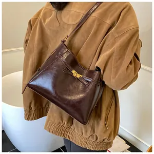Détail du sac cabas vintage marron foncé avec fermoir tournant porté sur une veste