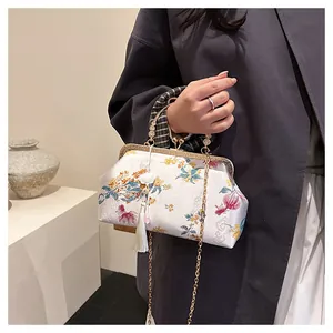Detail of white satin cheongsam bag with floral embroidery and gold metal clasp handle