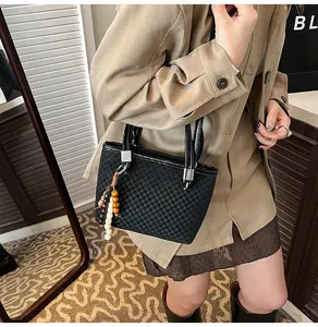 Close-up of black checkered bucket bag with beaded tassel and silver metal hardware