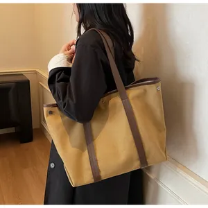 Detail of khaki canvas tote with dark brown leather straps and silver side snap buttons