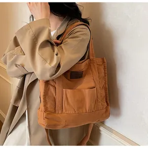 Close-up of caramel canvas tote bag with fashion luggage patch and exterior pocket detail