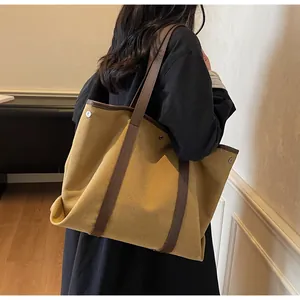 Detail of mustard canvas tote bag with brown leather straps shown on a model