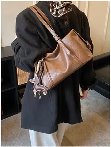 Detail of vintage brown oil wax leather shoulder bag with cute dachshund dog pendant charm