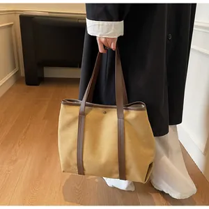 Close-up of large canvas tote bag with leather straps and metal snap button detail