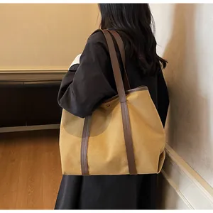 Large ginger yellow canvas tote bag with brown leather straps shown on shoulder