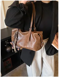 Brown vintage faux leather tote bag with tassel charm styled on a model in a black blazer