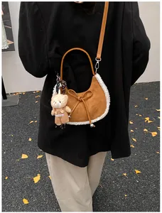 Detail of suede crescent bag with white faux fur trim and cute teddy bear pendant charm