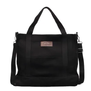 Stylish large capacity black canvas tote bag for commuting with brown logo patch and strap