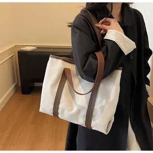 Close-up of a large canvas tote bag showing cream body and brown leather straps