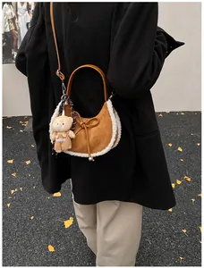 Detail of suede crescent bag with white faux shearling trim and bear charm