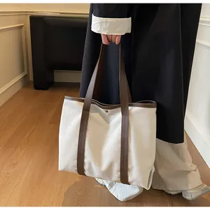 Detail of white canvas tote bag showing contrast brown handles and secure metal snap closure