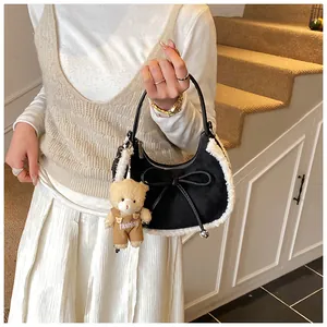 Detail of hobo bag with fuzzy trim and bear pendant on a neutral staircase