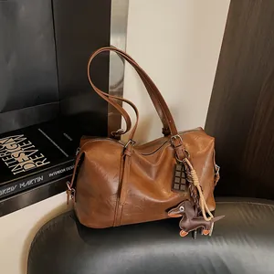 Brown oil-wax leather handbag with dachshund charm on a vintage armchair