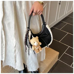 Detail of black suede crescent bag with faux shearling trim and cute bear charm