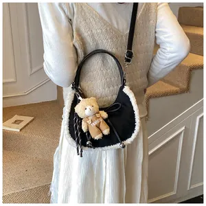 Detail of suede crescent bag with faux fur trim and cute bear charm accessory