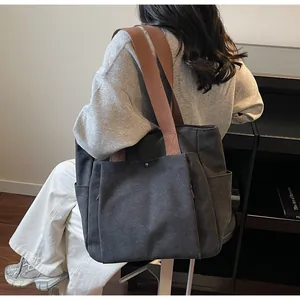 Detail of charcoal canvas tote bag featuring brown straps and functional metal snap pocket