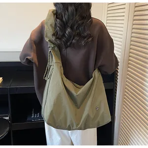 Army green nylon hobo bag with pleated shoulder strap worn by a model in a room