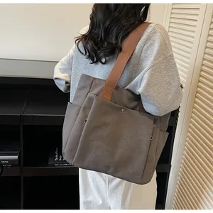 Detail of grey canvas tote bag with brown wide strap and large functional front pocket