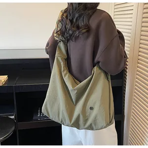 Close-up of olive green oversized tote bag with pleated strap and metal ring detail