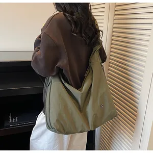 Detail view of large olive green pleated hobo bag with wide shoulder strap and metal logo
