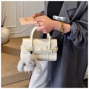 Detailed shot of white leather square handbag with gray plush bunny charm and flap cover
