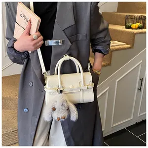 Detail of cream leather crossbody bag with cute plush rabbit charm and slim shoulder strap