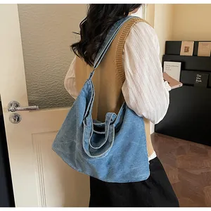 Macro detail of large blue denim tote bag with wide shoulder strap and washed texture
