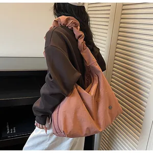 Detail of a large pink pleated tote bag with ruffled shoulder strap and metal logo