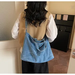 Blue washed denim tote bag with adjustable shoulder strap shown in a home scene