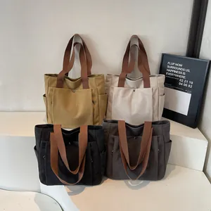 Minimalist canvas tote bags in four colors with brown woven handles and snap pockets