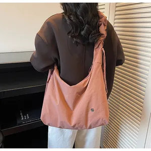 Detail of coral orange tote bag featuring pleated shoulder strap and minimalist logo mark