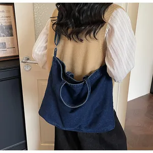 Macro detail of dark blue denim tote bag with long shoulder strap and top handles
