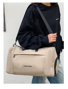 Outdoor model shot of a large beige Oxford fabric travel bag with a cross-body strap
