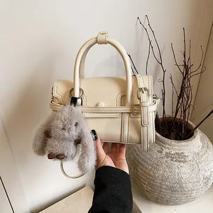 Chic beige crossbody bag with plush rabbit charm and top handle for women