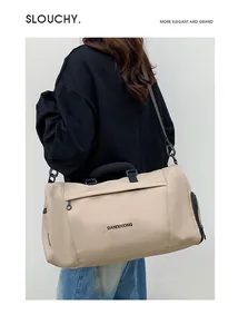 Detail of a beige large capacity travel bag with a side shoe compartment and black strap