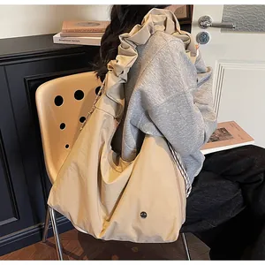 Detail of beige tote bag showing pleated shoulder strap and vintage metal buckle