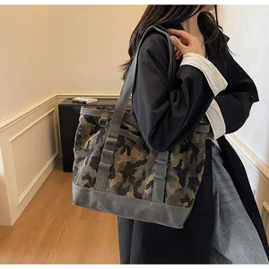 Detail of high-capacity camo canvas tote bag showing wide straps and metal side buckle